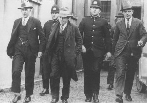 George Coats, flanked by police, was convicted of murdering Phyllis Symons in 1930 and burying her in earthworks at the construction of the Mt Victoria tunnel